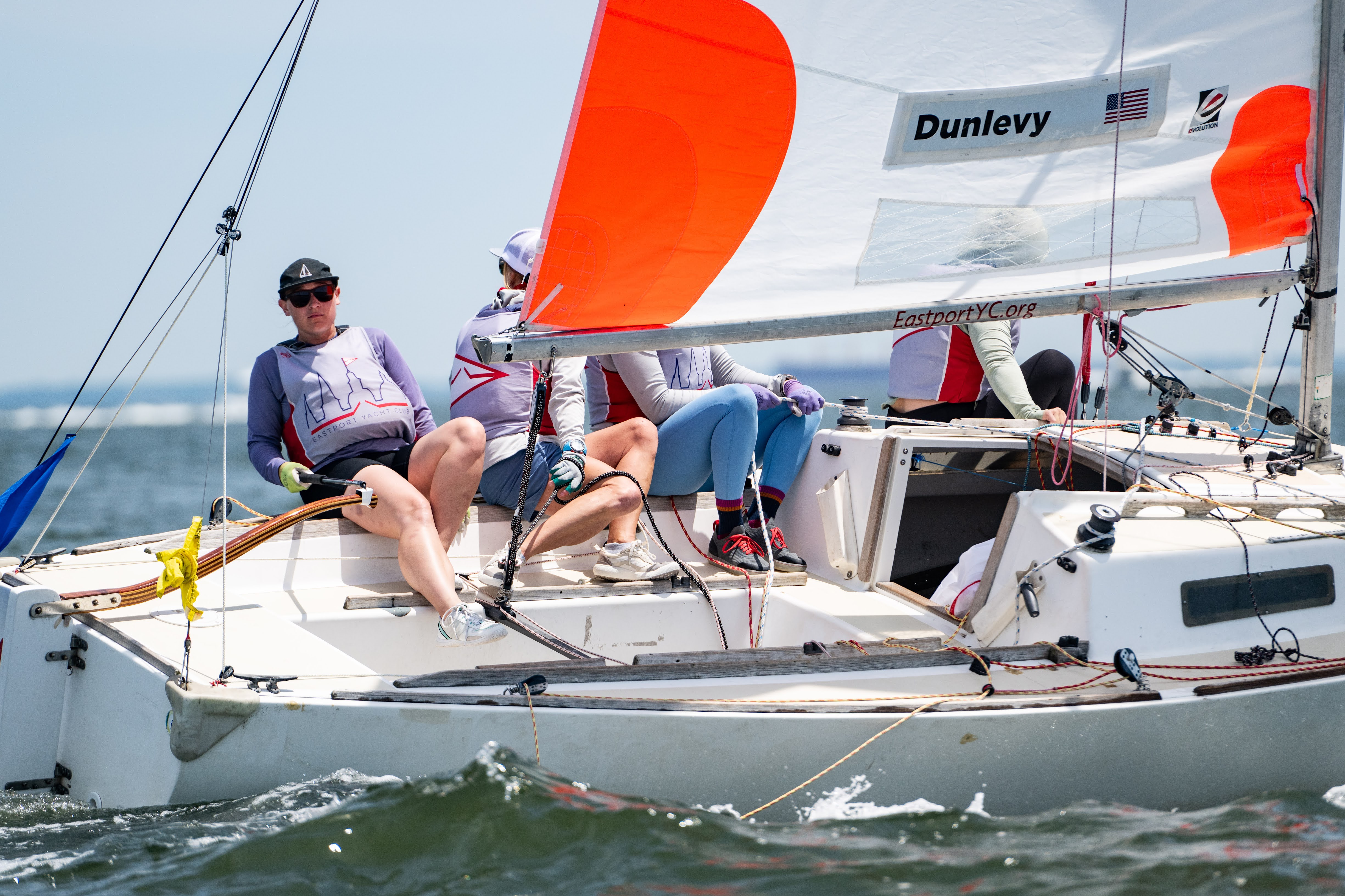 Crew racing under an orange spinnaker